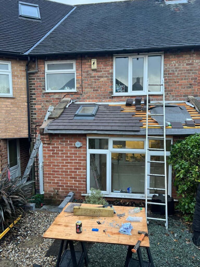 This is a photo of a roof extension that is having new roof tiles installed. This is a photo taken from the roof ridge looking down a tiled pitched roof on to a flat roof. Works carried out by Cambourne Roofing Repairs